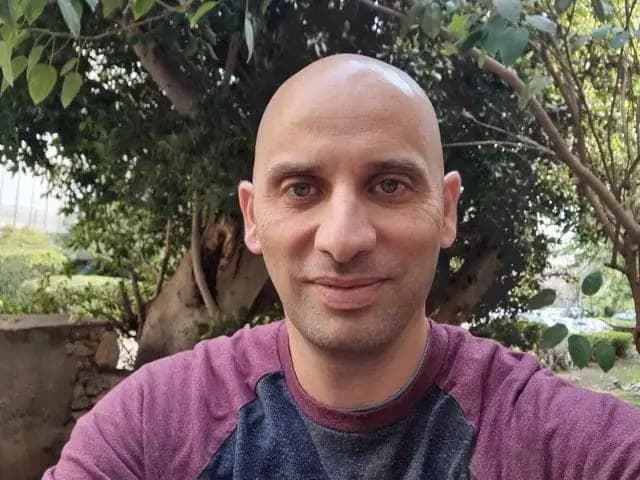 סלפי של גבר מחייך בחוץ, על רקע עצים
