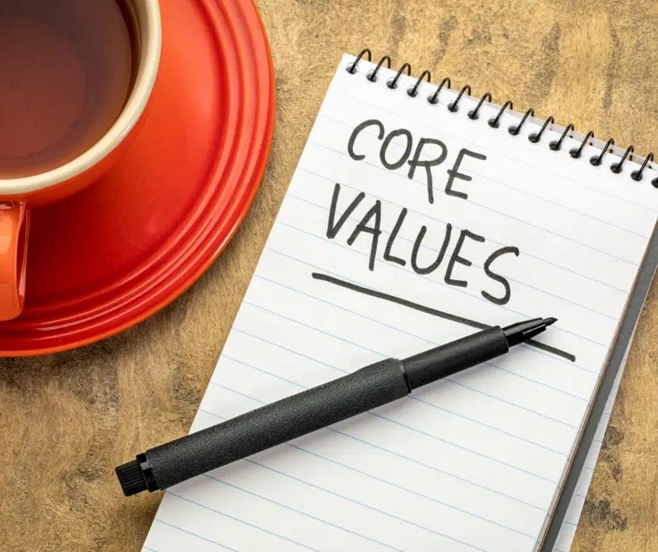מחברת פתוחה עם הכיתוב CORE VALUES, עט וכוס תה על שולחן